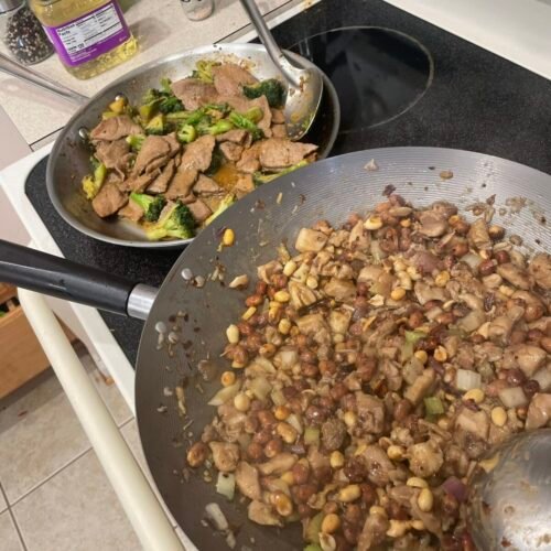 Homemade beef and broccoli and Kung Pao chicken cooking in separate pans